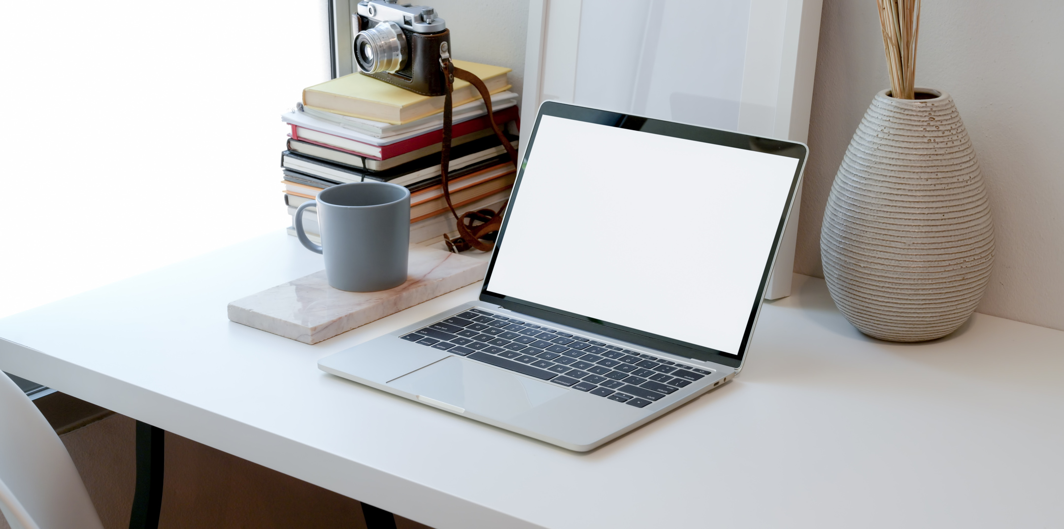 Laptop and cup of hot drink on white table